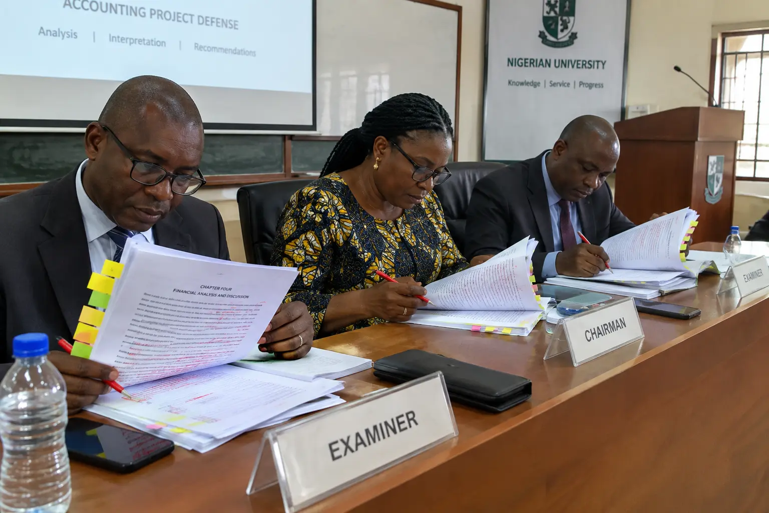 Examiners reviewing an accounting final year project chapter during defence