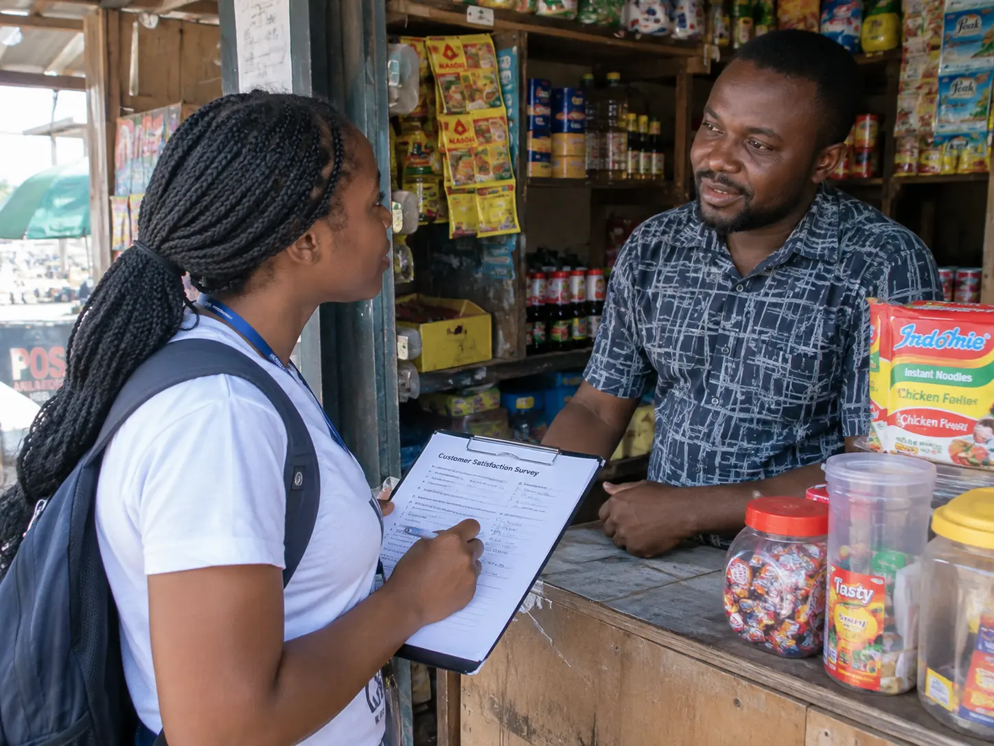 A student administering a short questionnaire to a Nigerian SME owner at their shop counter